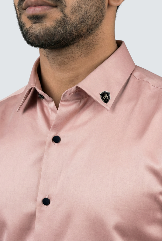 Close-up of a pink shirt with black buttons on a plain background