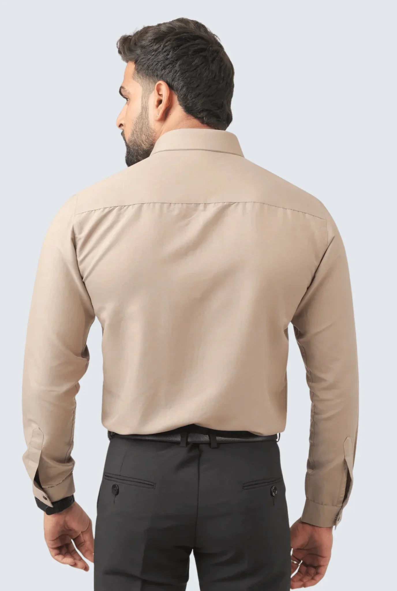 Back view of man wearing fawn cotton slim fit smart shirt with black trousers on light background