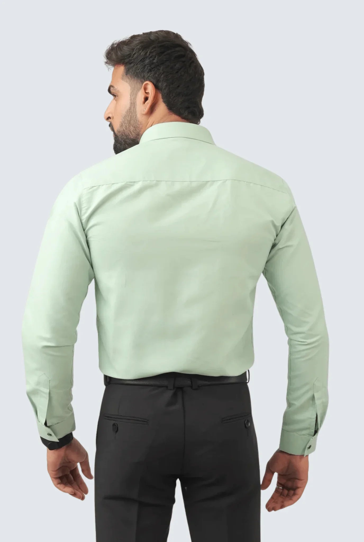 Back view of man wearing mint green slim fit cotton dress shirt with black trousers