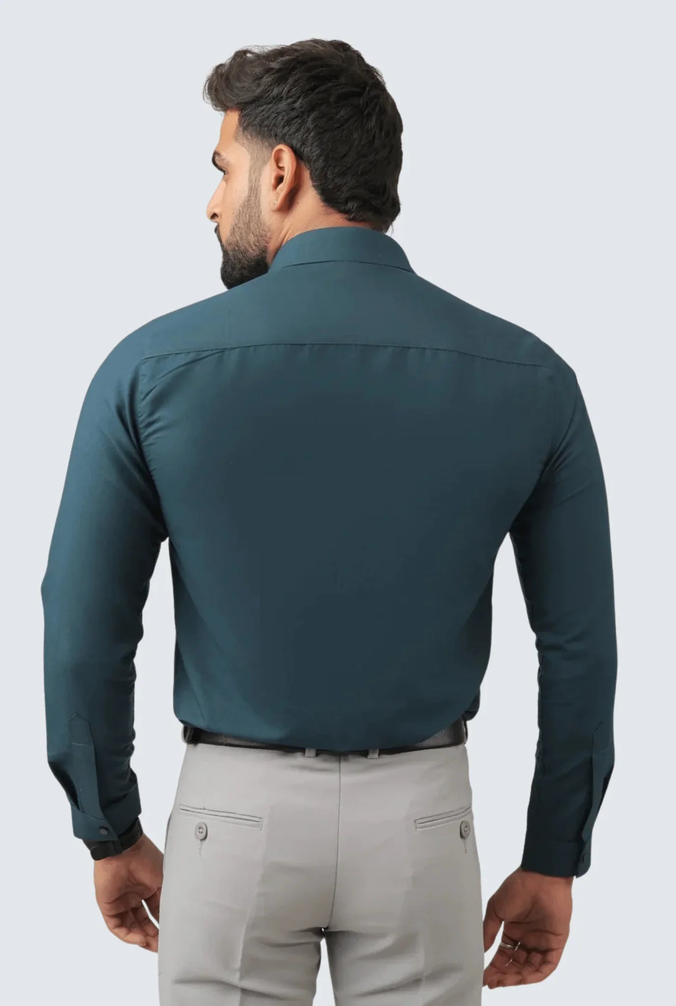 Rear view of man wearing slim fit teal blue cotton shirt and light grey dress pants