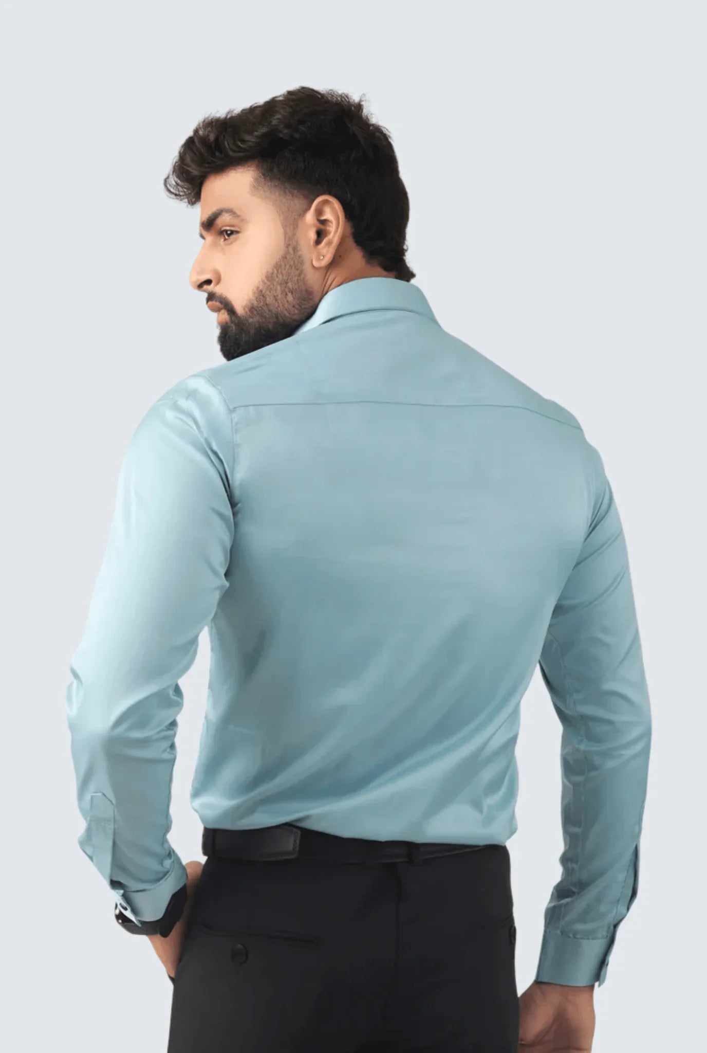Man wearing sky blue satin smart fit shirt paired with black formal pants against light background