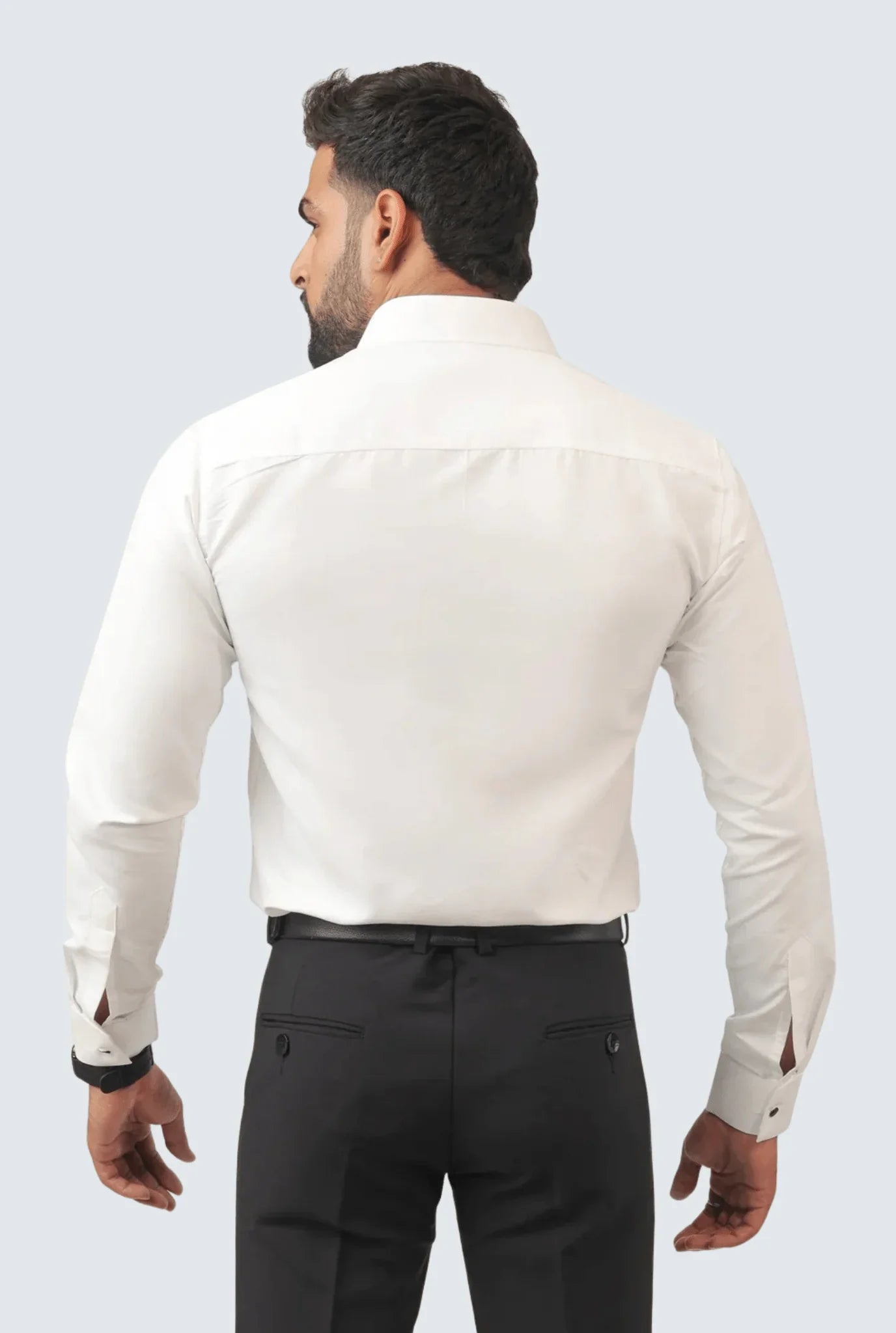 Back view of man wearing white slim fit cotton dress shirt with black trousers on grey background
