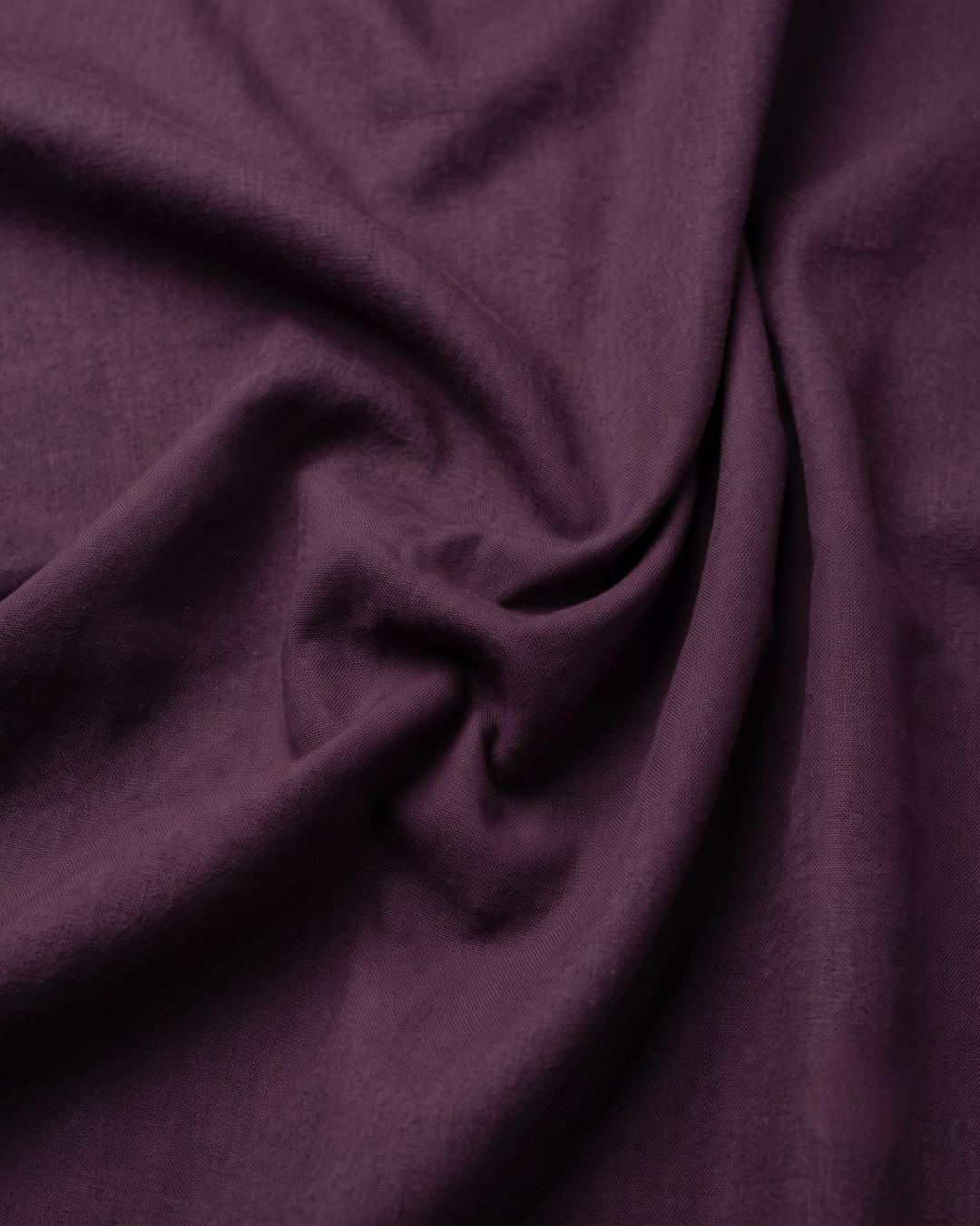 Dark purple cotton shirt fabric closeup, smooth weave and soft drape