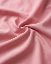 Pink cotton shirt fabric close-up with soft drape and wrinkles