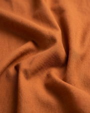 Golden-orange cotton shirt fabric close-up, smooth woven texture