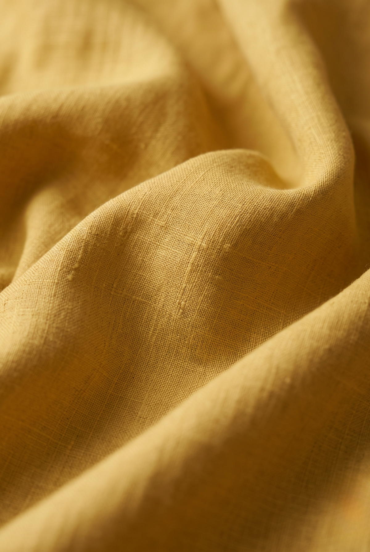 Close-up of yellow linen fabric with visible weave texture and soft drape