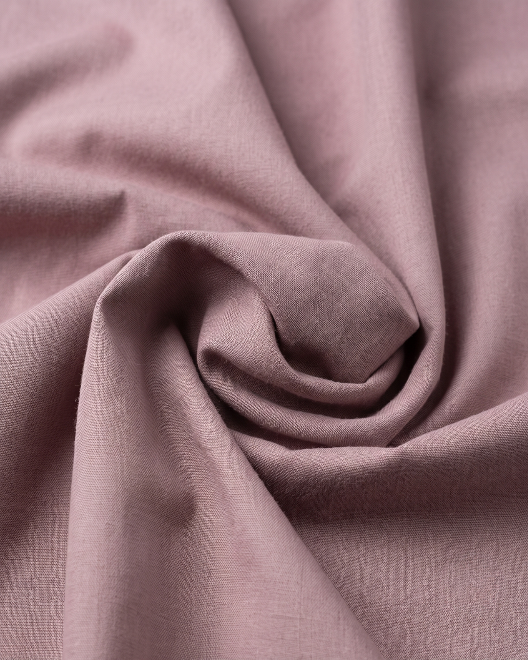 Mauve cotton fabric close-up with smooth woven texture and slight folds.