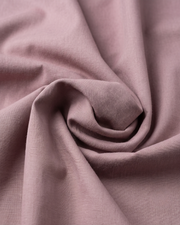 Mauve cotton fabric close-up with smooth woven texture and slight folds.