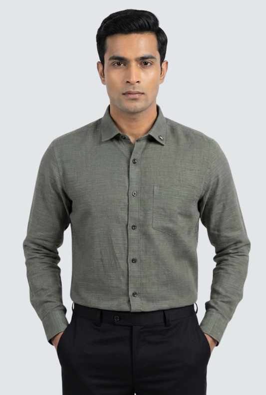 Man wearing a gray button-up shirt and black pants on a light gray background