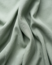 Light green cotton fabric close-up with soft wrinkle texture