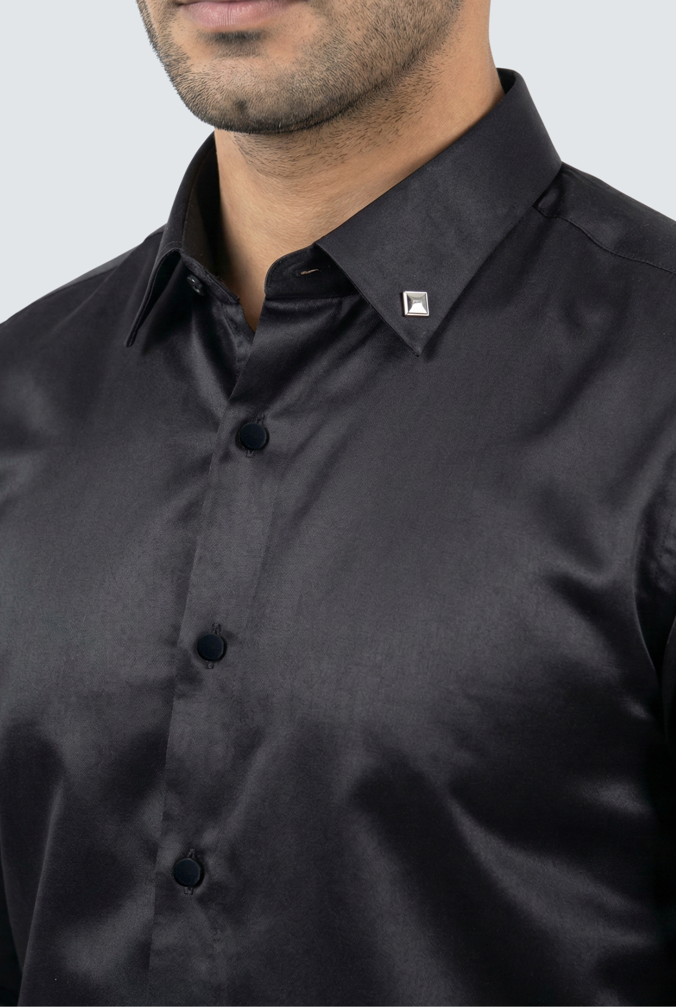 Close-up of a black dress shirt with a brand logo on a light gray background