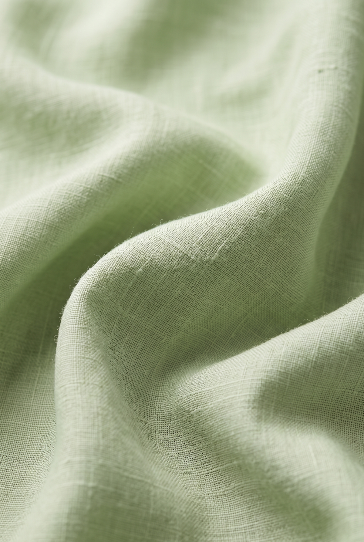 Light green linen fabric close-up showing visible weave texture