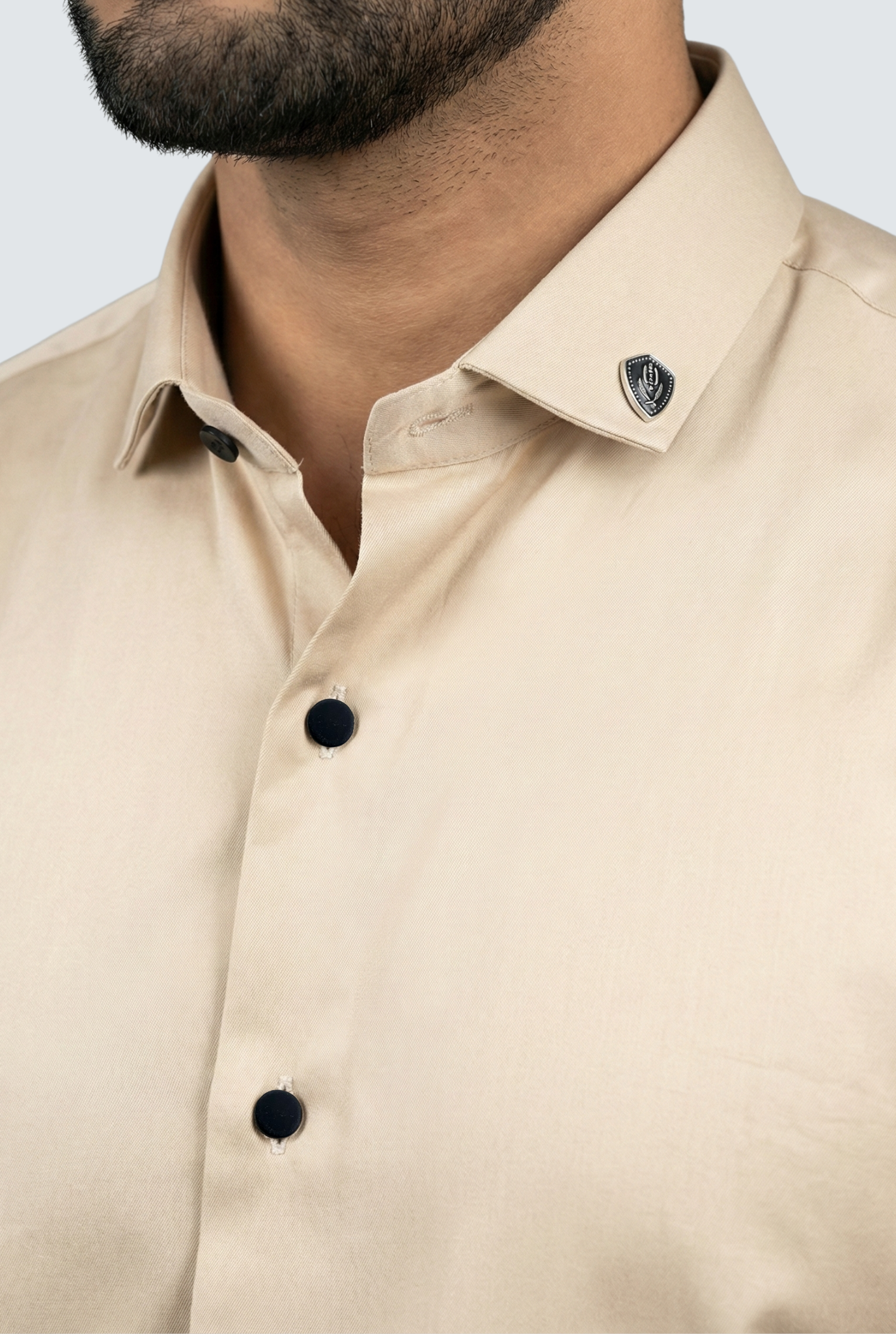 Close-up of a beige shirt with black buttons on a light gray background