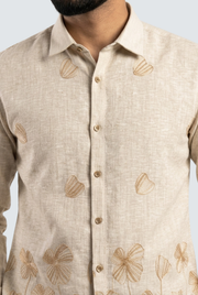 Cream linen shirt front with pointed collar, button placket, and floral leaf print.