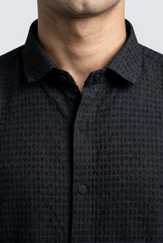 Black textured shirt close-up with buttoned placket and pointed collar