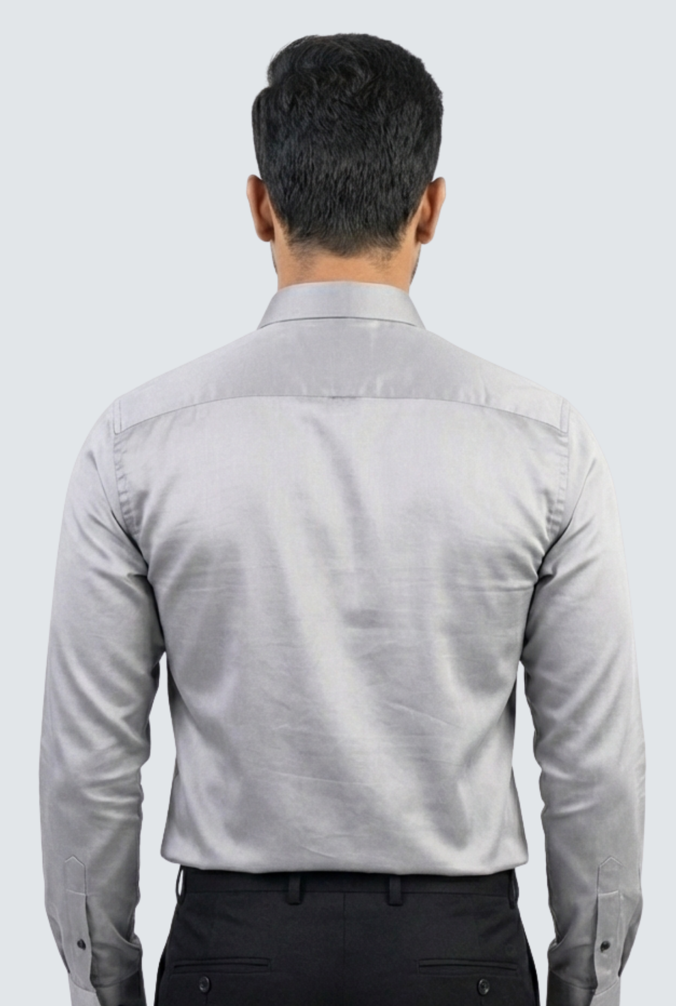 Man wearing a light gray dress shirt from behind on a white background