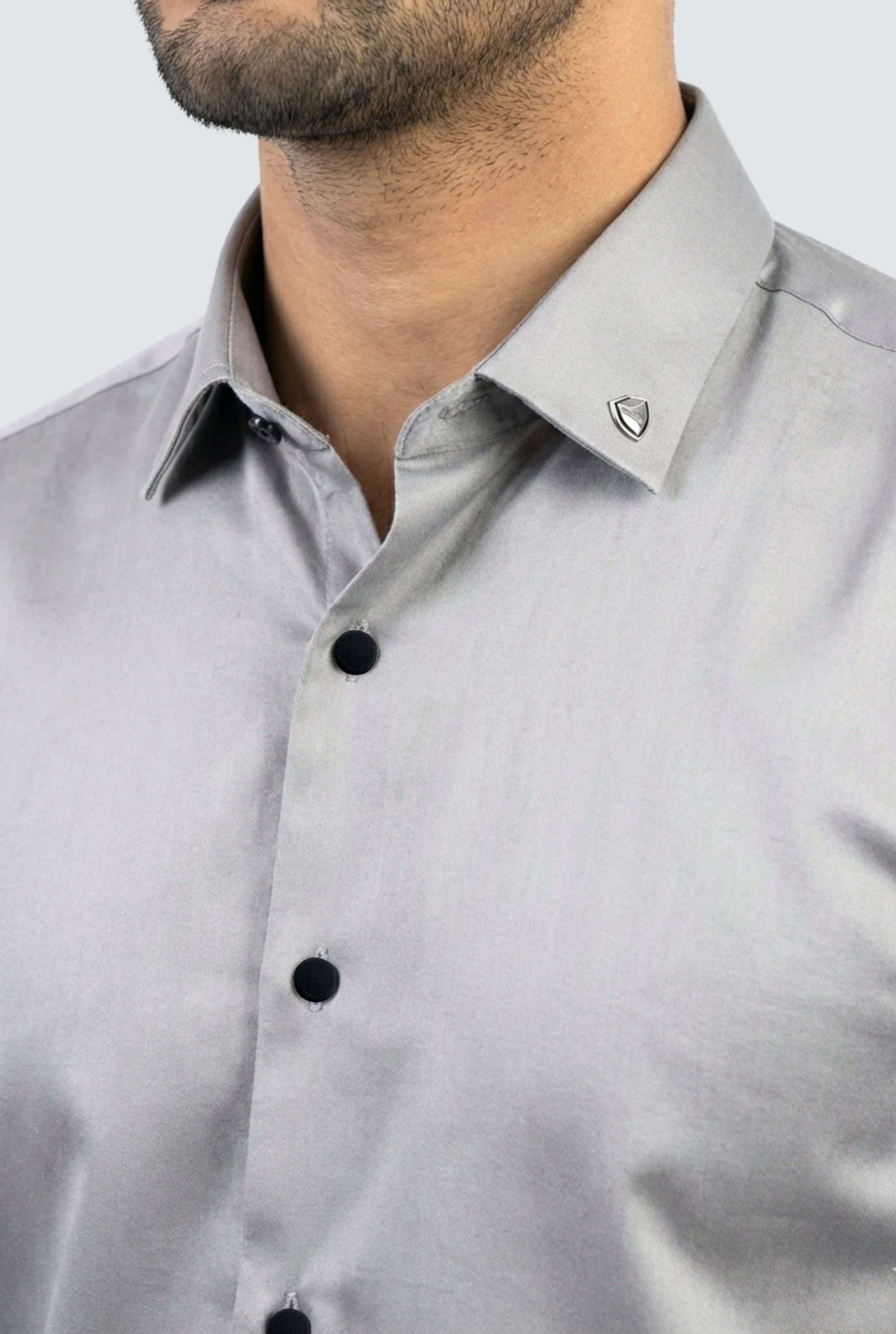 Gray dress shirt with black buttons worn by a person on a light gray background
