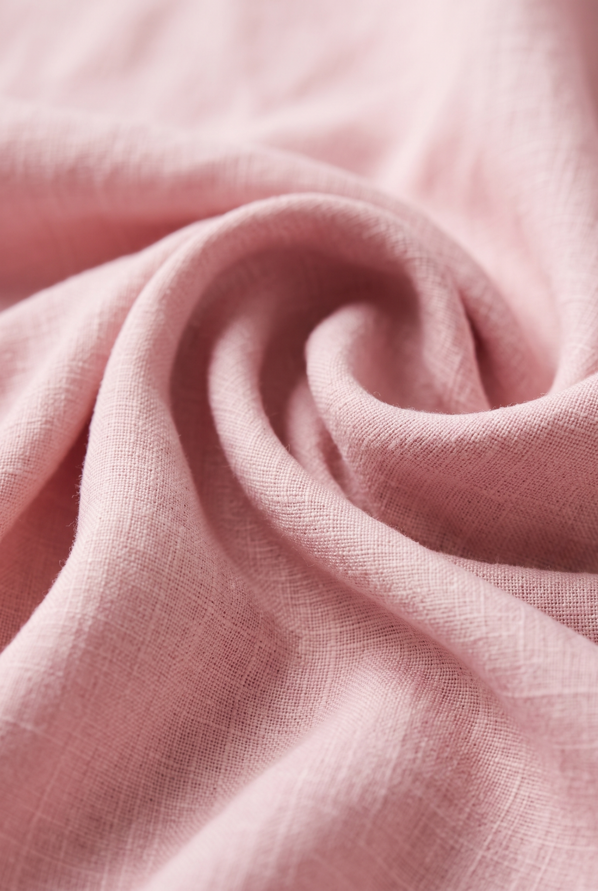 Pink linen fabric close-up showing woven texture and draped folds.