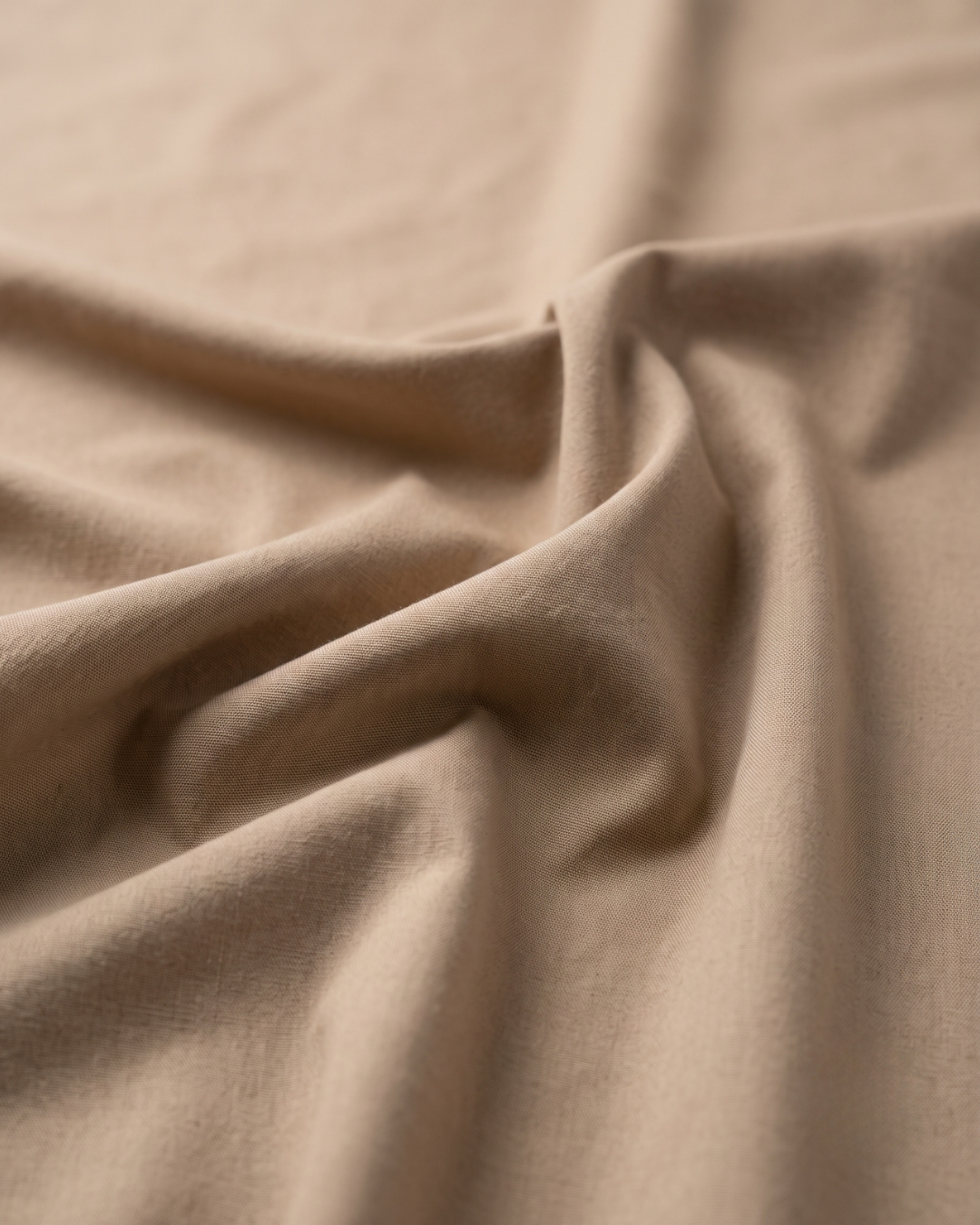 Fawn cotton fabric close-up with soft drape texture