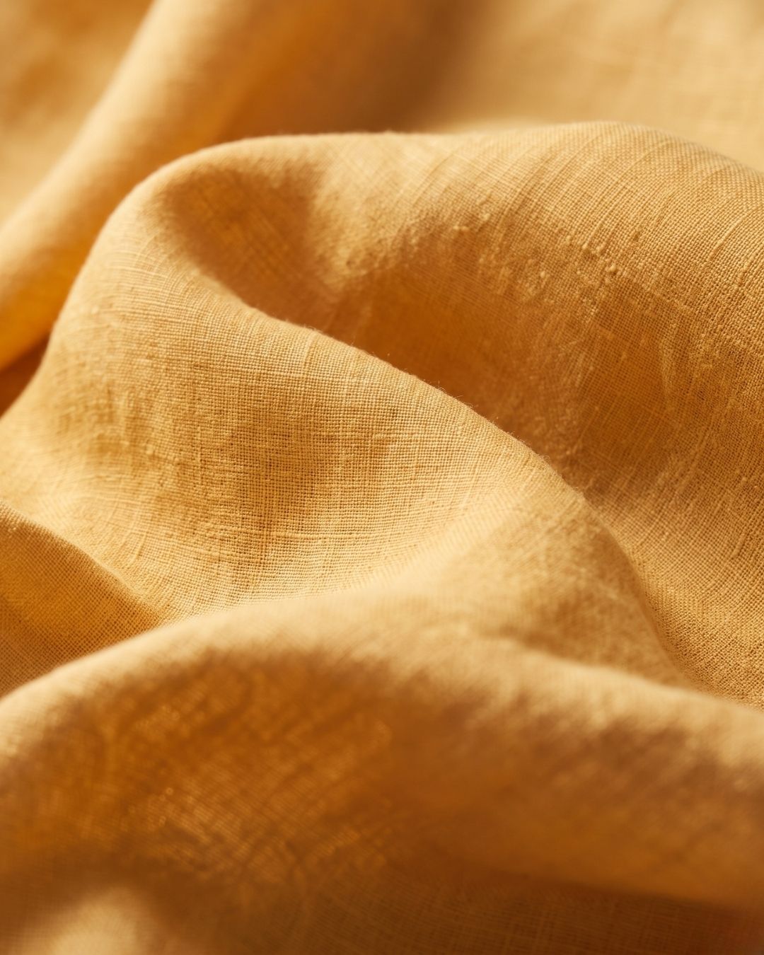 Yellow linen shirt fabric close-up showing its textured weave