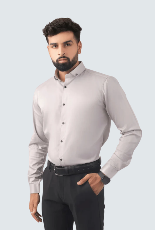 Man wearing a light gray dress shirt and dark pants on a light gray background